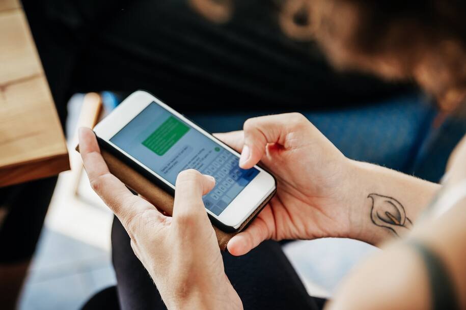 Hands holding a smartphone while scheduling a text message to send later